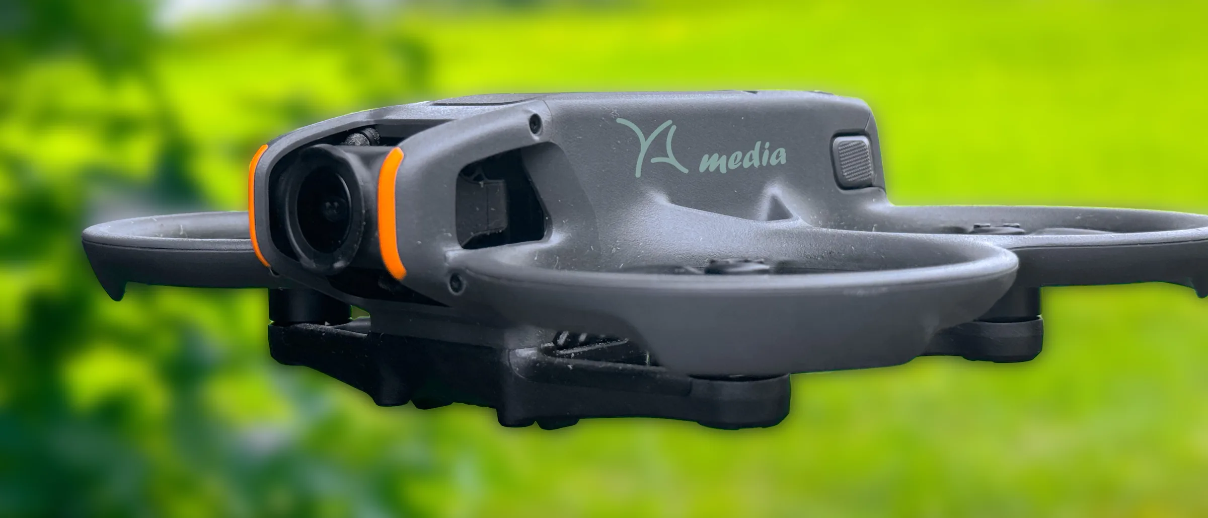 FPV-Drohne von YA-media mit Propellerschutz im Flug vor grüner Wiese – Drohnenaufnahmen aus München